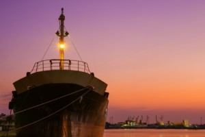 An old oil tanker ship is moored in shipyard area at harbor during renovation work against colorful pink twilight sky background