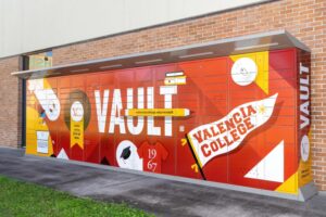 A wall of orange and red package lockers outside of a brick building