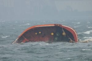 The bow of an orange oil tanker, with the rest of the sip sunk beneath the water