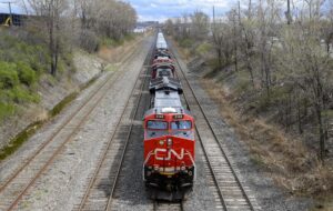 A head-on view of a red train with trees on either side of the tracks