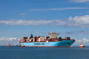 A blue Maersk container ship at sea carrying stacks of shipping containers