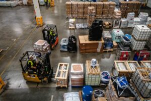 A BIRD'S EYE VIEW OF A BUSY WAREHOUSE, WITH GOODS ON PALLETS AND FORKLIFT TRUCKS