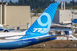 The back-half of a blue and white airplane, with "777" written in large white letters across the tail