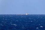 A cargo ship in the distance, sitting in a wide open sea