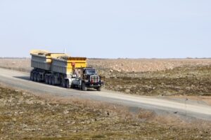 A large truck carrying rocks driving down a remote road