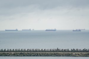 A LINE OF TANKER SHIPS FAR OFF ON THE SEA'S HORIZON