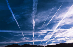 MULTIPLE WHITE VAPOR TRAILS STREAK ACROSS A BLUE SKY