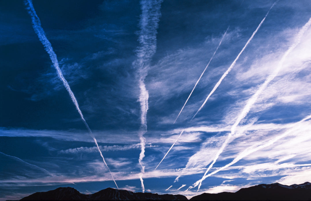 MULTIPLE WHITE VAPOR TRAILS STREAK ACROSS A BLUE SKY