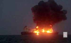 An oil tanker on fire, with smoke billowing into the sky