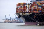 A CONTAINER SHIP APPROACHES THE DOCK AT A MAJOR PORT