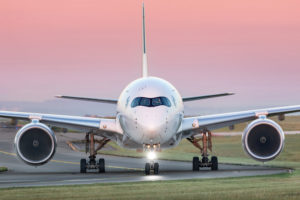 AN AIRPLANE TAXIS ON A RUNWAY AGAINST A ROSE COLORED SKY