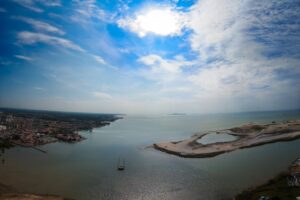 A large waterway with land on either side set against a blue clouded sky