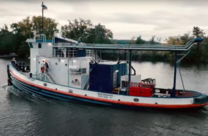 A blue and white tugboat flying an American flag, with the words "NH3 KRAKEN" written on the side