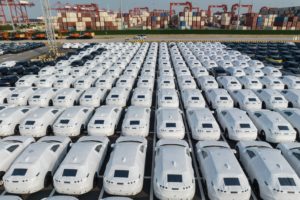 Dozens of cars lined up in a grid, each with a white covering