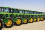 A row of green tractors with yellow hubcaps