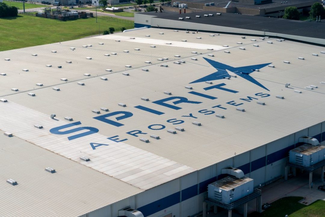 THE ROOF OF A LARGE WAREHOUSE BEARS THE WORDS SPIRIT AEROSYSTEMS