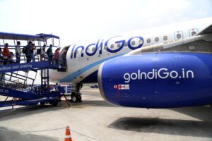 Passengers boarding a blue and white airplane, with "IndiGo" written in blue letter across the side