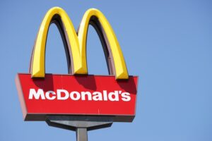 A large yellow 'M' on a signpost, above "McDonald's" written in white lettering on a red background.