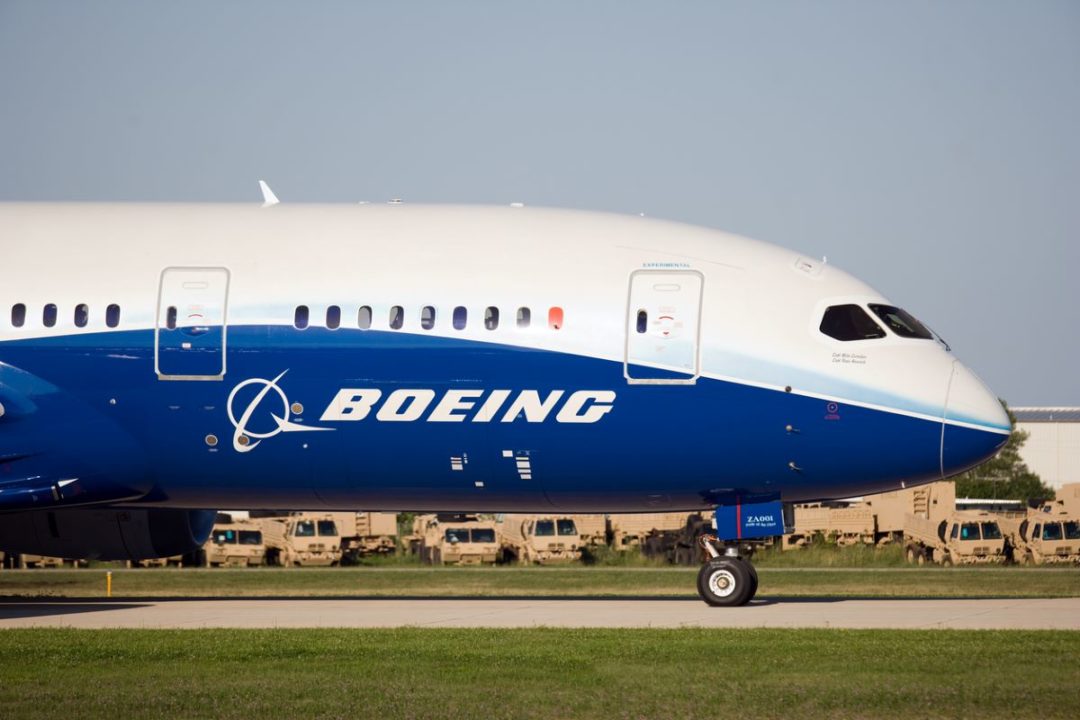 A HUGE AIRPLANE WITH BOEING WRITTEN ON THE SIDE ROLLS ALONG AN AIRPORT RUNWAY