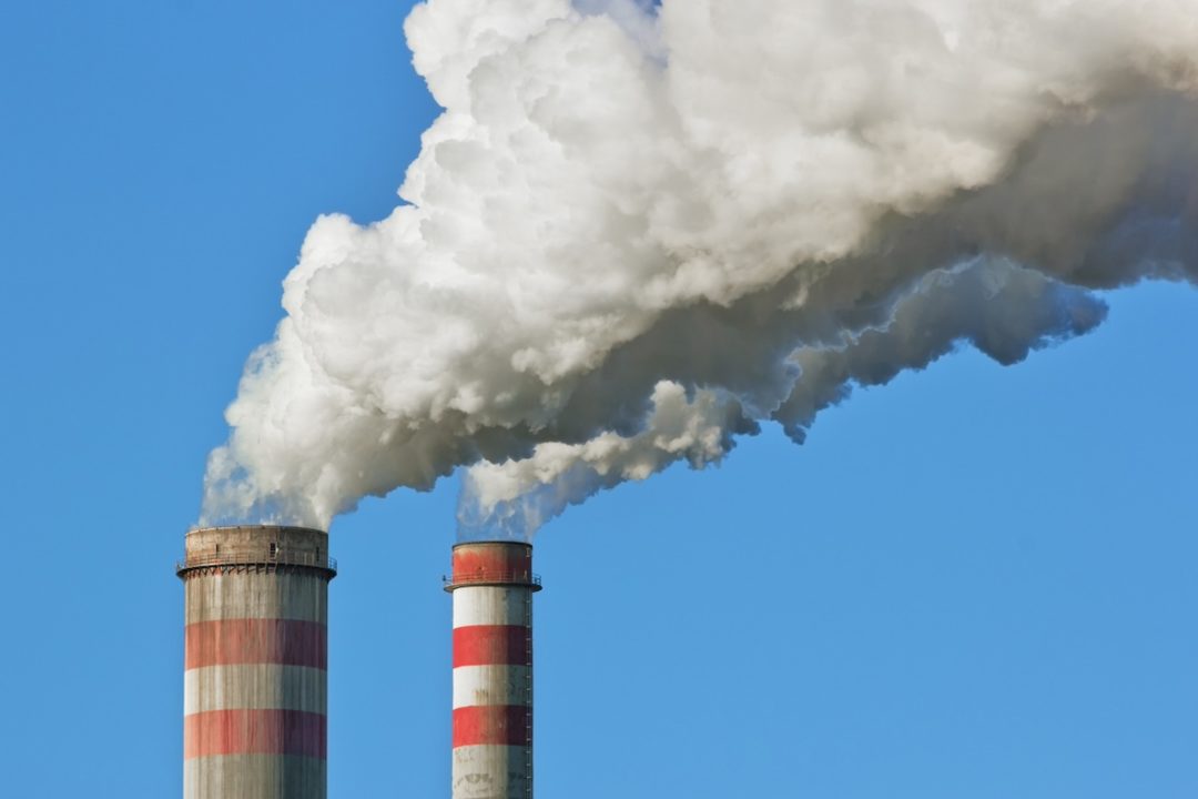 Two red and white striped smokestacks, spewing clouds of white smoke into the air