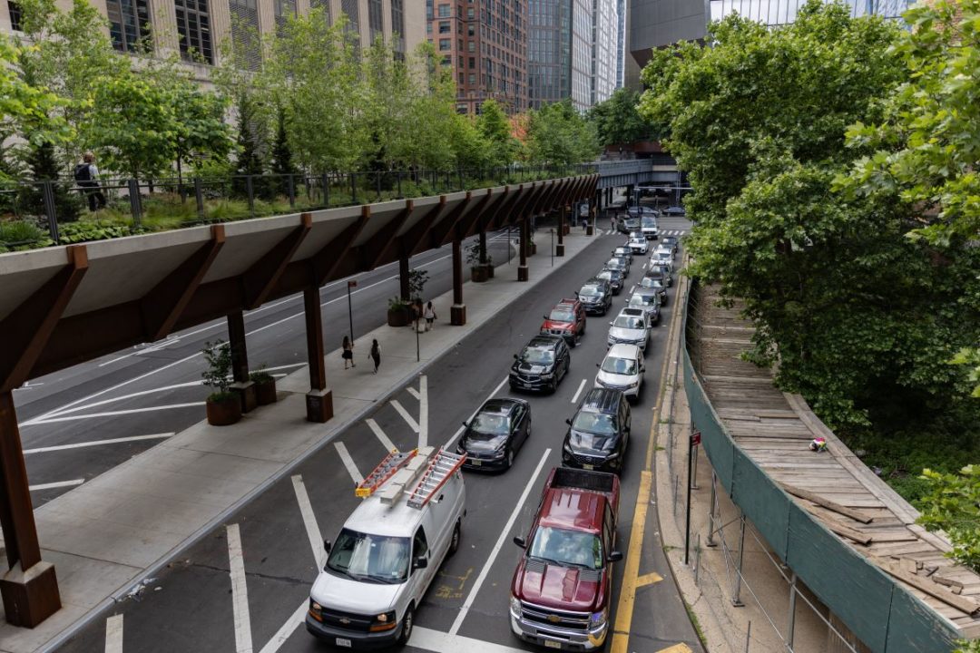 TWO LONG LINES OF TRAFFIC SIT ON A RAMP DOWN TO A TUNNEL