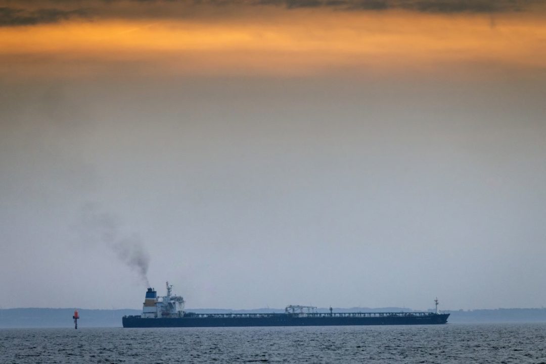 AN OIL TANKER PLIES THE SEAS UNDER A GREY AND APRICOT SKY