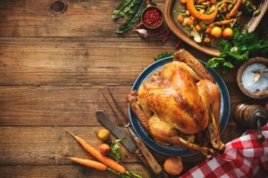 An overhead view of a cooked turkey on blue serving plate sitting on a wood table.