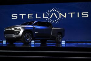 A GLEAMING NEW, SAPPHIRE COLORED PICKUP TRUCK SITS ON A POLISHED FLOOR, THE WORD STELLANTIS PICKED OUT IN LIGHTS BEHIND IT