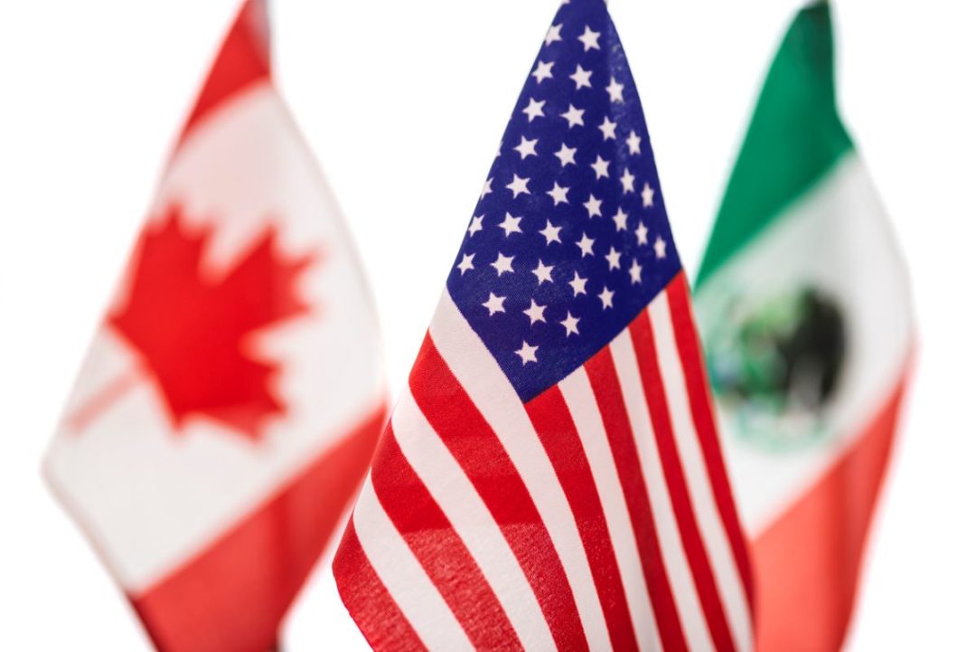 MINIATURE FLAGS OF US CANADA AND MEXICO ARE CLUSTERED TOGETHER, THE US ONE IN THE FOREGROUND