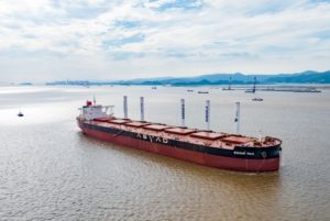 A LARGE OCEAN-GOING VESSEL WITH FIVE CYLINDRICAL STRUCTURES RISING FROM ITS DECK MAKES IT WAY ACROSS THE SEA