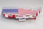 A RED WHITE AND BLUE PAINTED PLANK CUT IN THE SHAPE OF THE UNITED STATES IS SURROUNDED BY A CLEAR PLASTIC WALL, AND FESTOONED WITH  SIGNS SAYING TARIFFS AND 10%, 80%, 100%