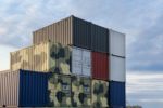 A STACK OF CONTAINERS CONTAINS FOUR PAINTED IN MILITARY CAMOUFLAGE