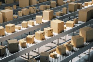 IN A WAREHOUSE, MULTIPLE CONVEYOR BELTS HOLD PLAIN BROWN BOXES OF MANY SIZES