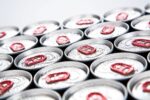 EXTREME CLOSEUP OF A CLUSTER OF SOFT DRINKS CANS WITH RED TAG PULLS.