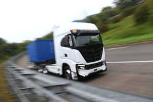 AN ELECTRIC TRUCK DRIVES DOWN A HIGHWAY, BLURRED TO SHOW SPEED