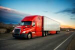 A TRUCK DRIVES DOWN A HIGHWAY AT SUNSET