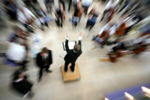 A STYLIZED BLURRY AERIAL SHOT OF A CONDUCTOR CONDUCTING AN ORCHESTRA