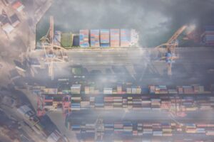 A shipping port with multi-colored containers stacked in rows seen from above, blanketed in fog